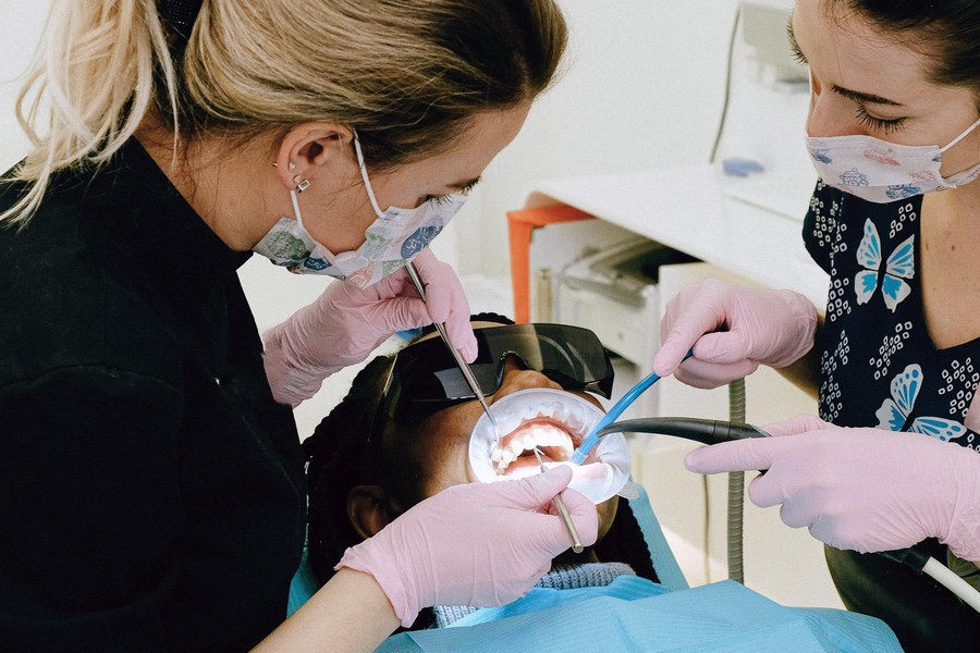 Dental assistants in scrubs working on patient in practice