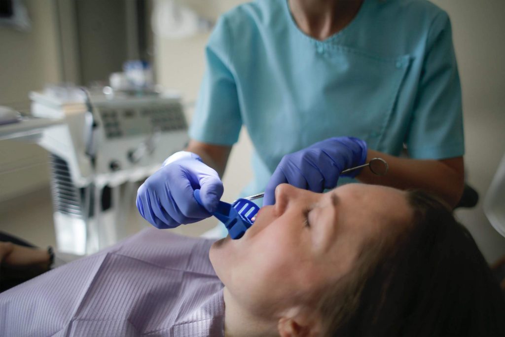 Dental assistant working on patient in exam room during appointment