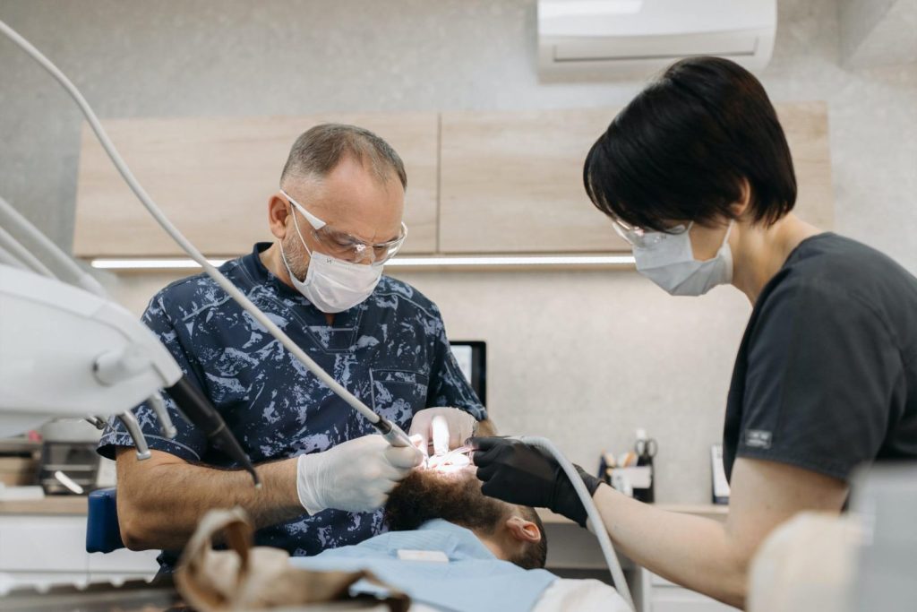 Dental assistant following dentist's instructions while working on patient in exam