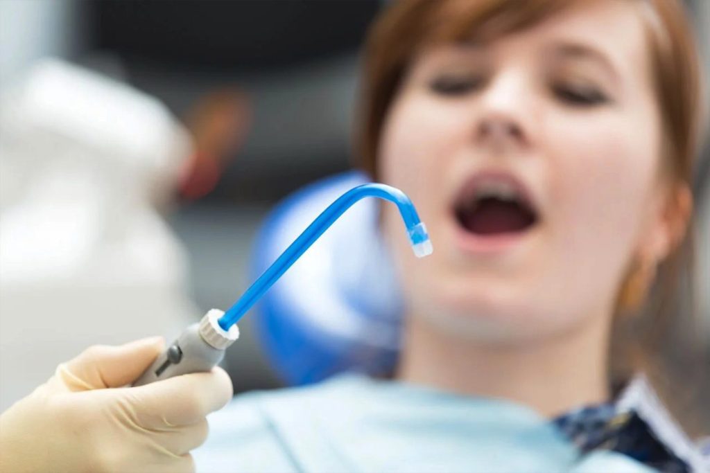 Dental suction tool near mouth of patient in practice
