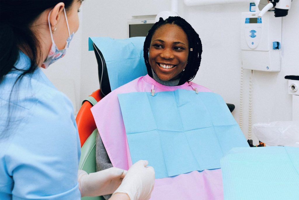 Dental assistant listening to smiling patient during appointment