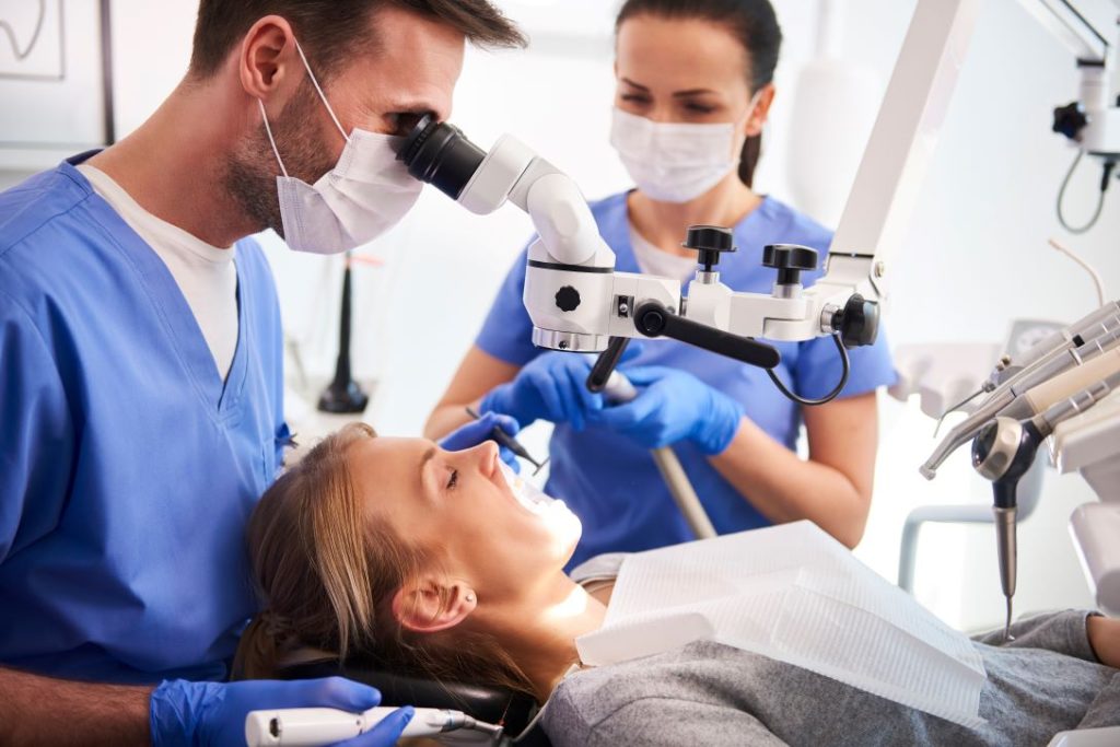 Dentist and assistant working using device to look inside patient's mouth