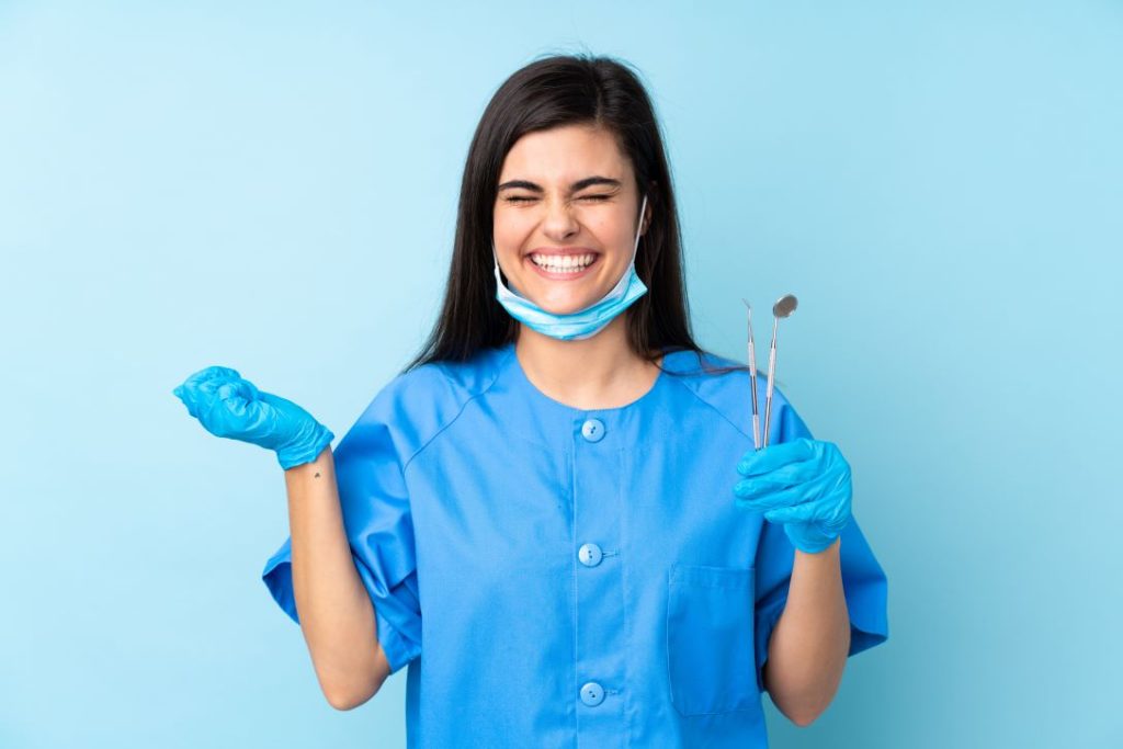 Smiling dental assistant with tools in hand