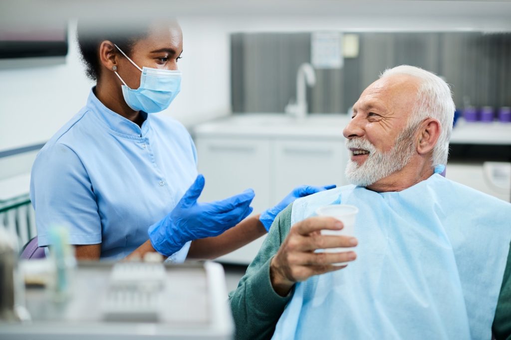 Dental assistant having friendly conversation with patient to relax them during exam