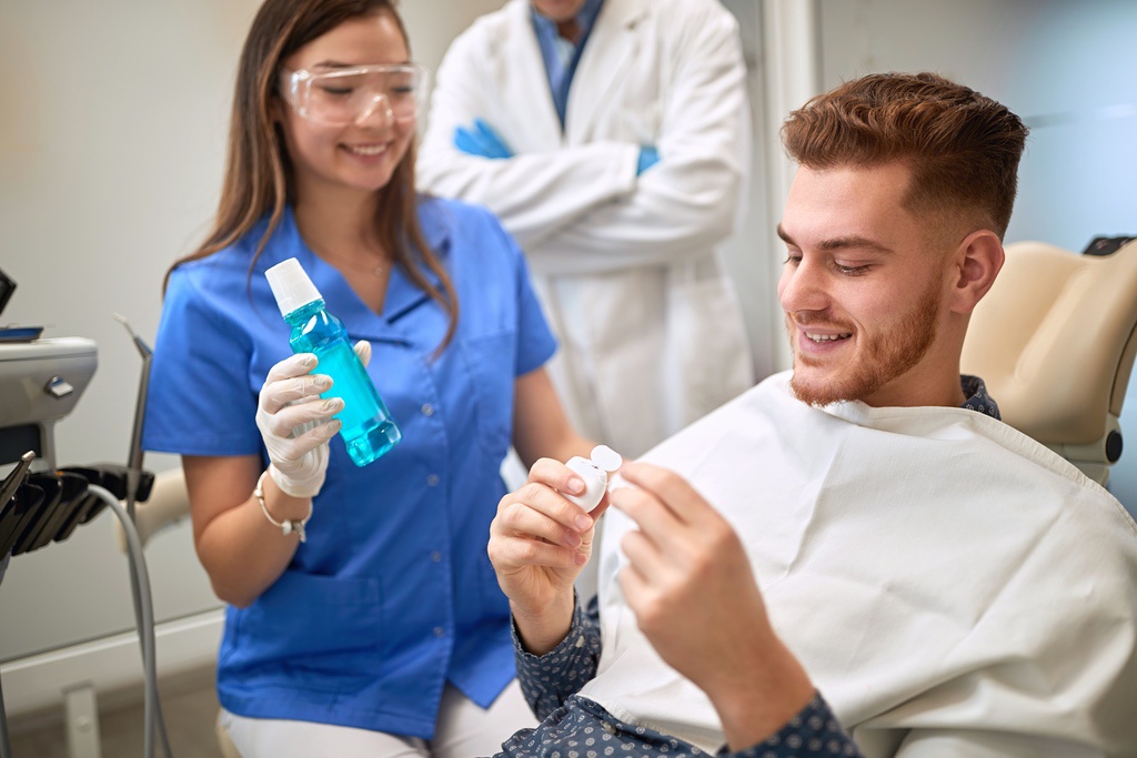Dental assistant explaining flossing and mouthwash to patient