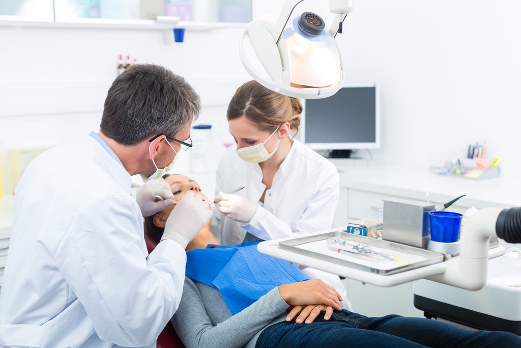 Dental assistant providing assistance to dentist during appointment
