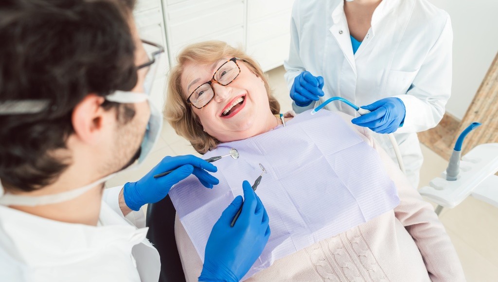Patient in dental chair smiling while dental assistant talks with them to calm their nerves