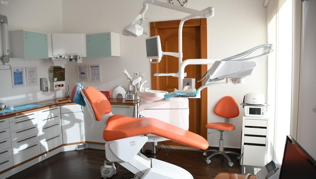 orange dental chair, dentist, teal cabinets, wood floors, white equipment