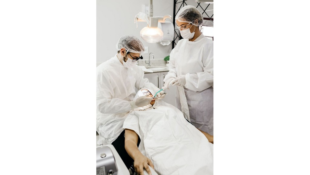 oral surgery, hair nets, glasses, white room, white clothing cover, white masks, blue suction tube