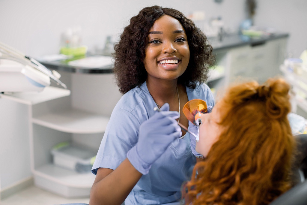 Dental assistant smiling and maintaining positive attitude while working with patient in exam room