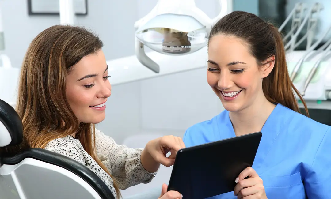 Dental assistant and patient smiling in dentist's office