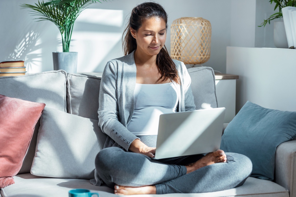 Woman sitting in morning sunlight and completing module on laptop before normal school hours