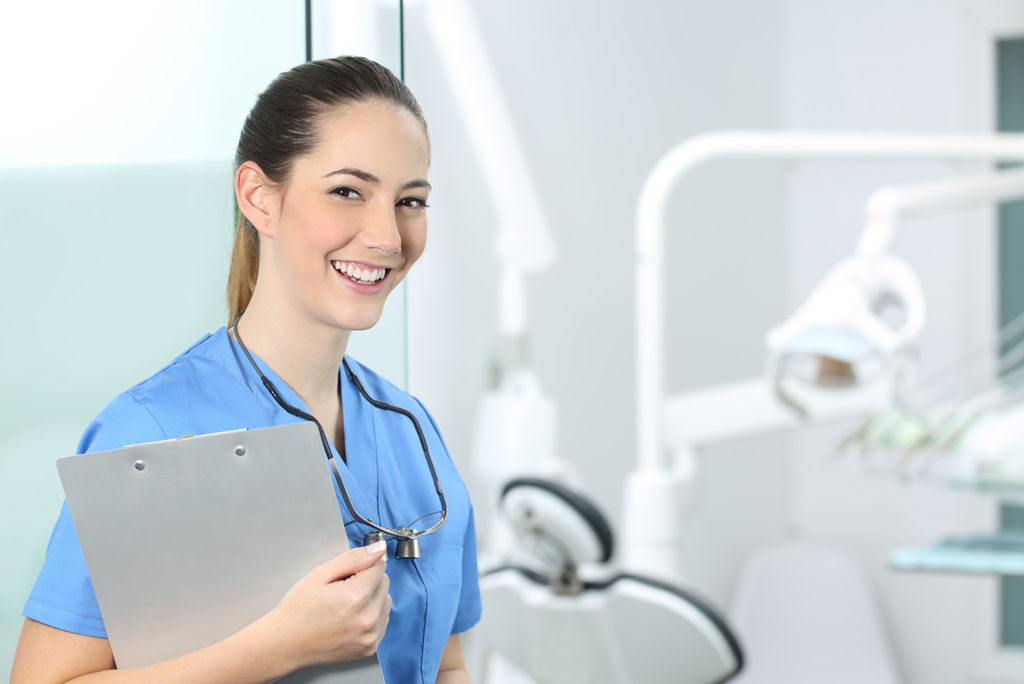 Smiling dental assistant with equipment in the background
