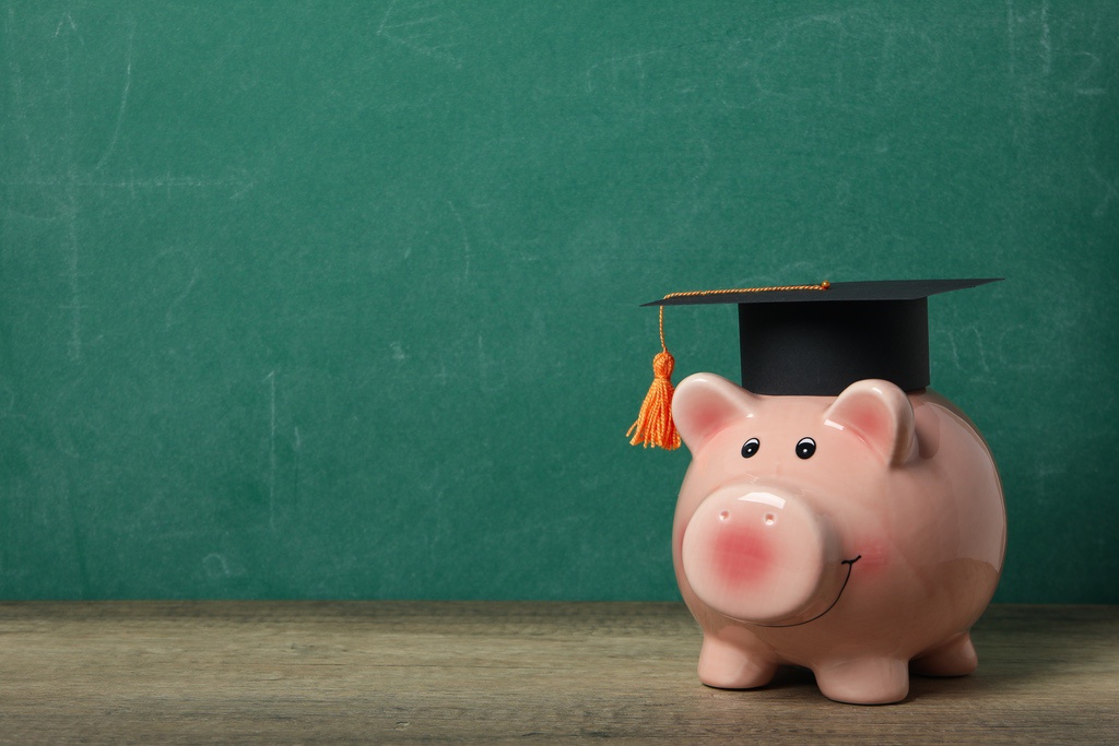 Piggy bank with high school graduation hat to symbolize saving money with cost-effective online education like Risio's Dental Aide Program