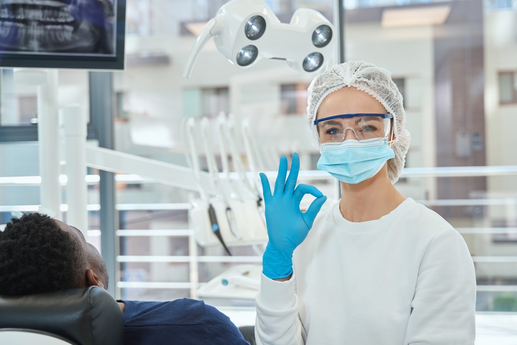 Dental assistant giving positive hand gesture in thriving practice
