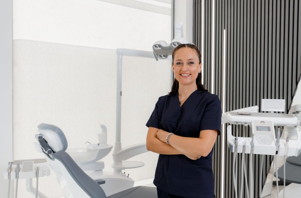A dental assistant smiling with their arms crossed in the exam room.